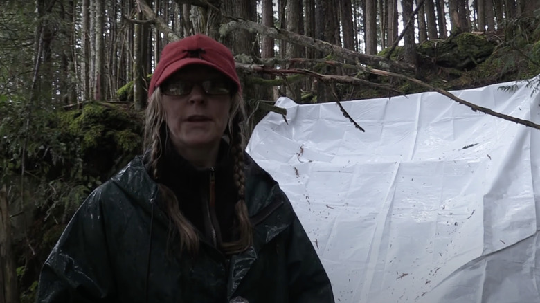 Woman speaking into camera next to tent in woods
