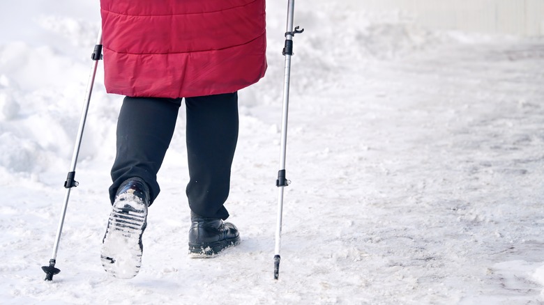 Person using trekking poles on snowy ground