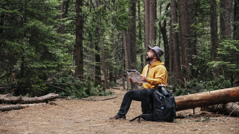 Hiker alone, looking up from map