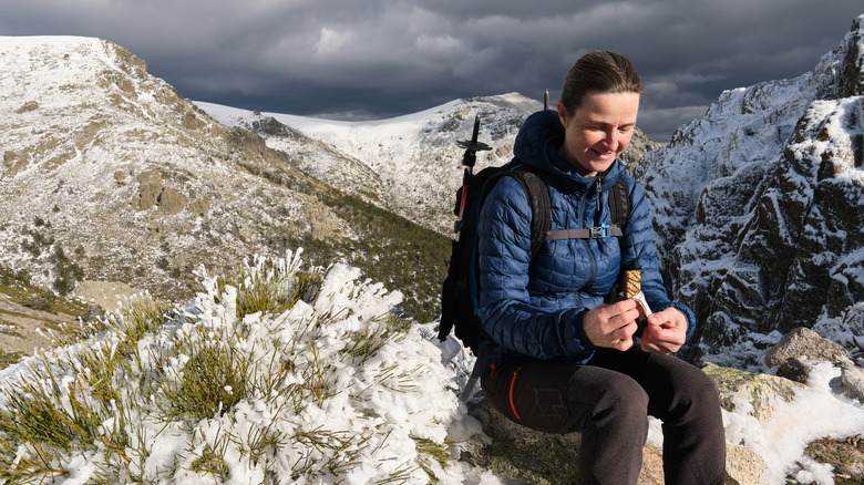 Woman eating a granola bar during winter hike