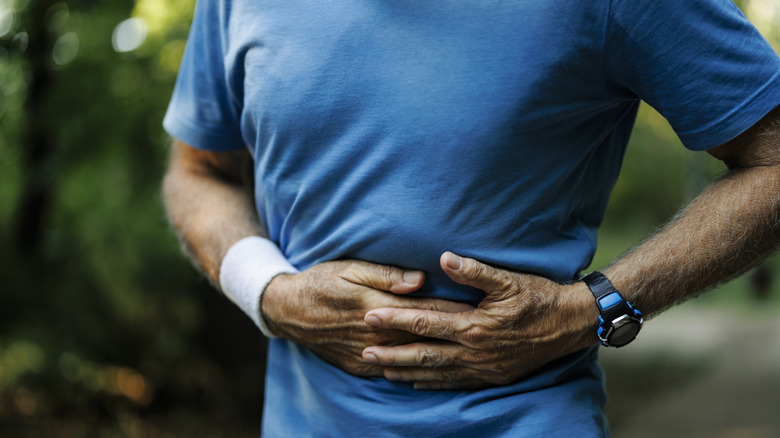 Man holding side of stomach, close-up