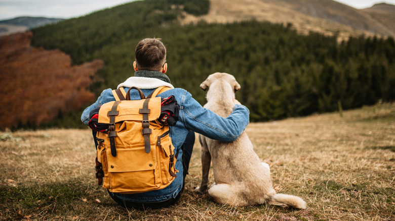 Hiker seated with arm around dog